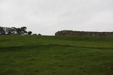 Obraz premium Landscape view of ancient monument Hadrian’s Wall. the rugged Scottish highland countryside, a dramatic historical landmark set against a windswept moorland backdrop