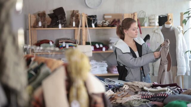 Young woman near showcase examine goods, buying trousers. Off line clothing store from retailer. Style and fashion type look, modern trends. Designer clothing store, vintage fashion, limited edition