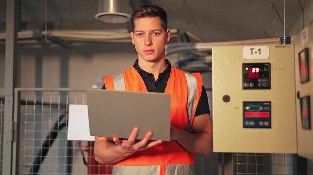 Engineer works with laptop in technical control room. Diligent individual monitors complex systems, ensuring efficiency and safety. Shows professionalism, focus, and responsibility.