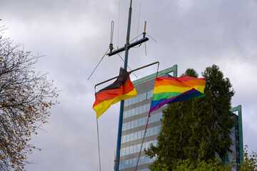 German flag and rainbow flag waving at riverbank of Main River at German city of Frankfurt on an...