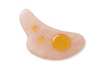 Gua sha massage tool made from natural rose quartz with drops of nourishing facial oil, focusing on self-care and beauty treatments