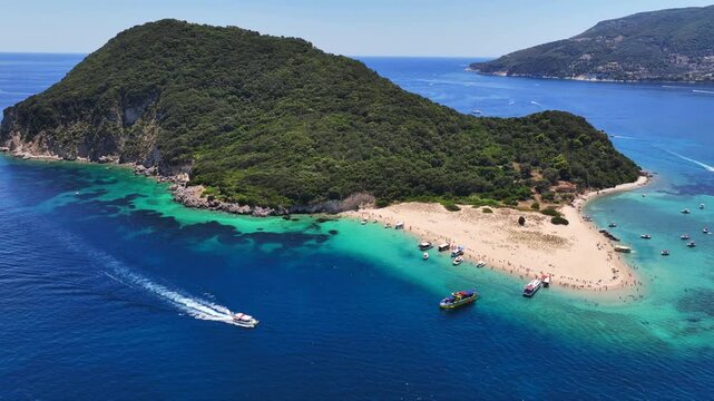 Aerial drone cinematic video of scenic caves and turquoise beach in paradise island of Marathonisi in bay of Laganas, visited by small boats a true tourist attraction, Zakithnos island, Ionian, Greece