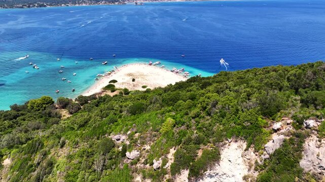 Aerial drone cinematic video of scenic caves and turquoise beach in paradise island of Marathonisi in bay of Laganas, visited by small boats a true tourist attraction, Zakithnos island, Ionian, Greece