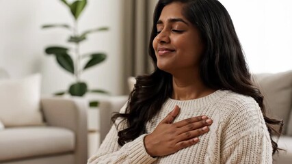 A young woman practices a deep breathing exercise with her hand on her chest. Managing stress and anxiety through mindfulness. Mental health and self-care concept
