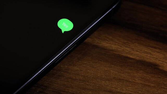 Close-up view of a smartphone screen showing an outgoing &ldquo;yes&rdquo; text message in a green bubble, captured as it sends with a smooth popup animation.