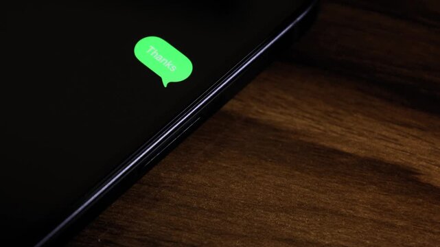 Close-up view of a smartphone screen showing an outgoing &ldquo;thanks&rdquo; text message in a green bubble, captured as it sends with a smooth popup animation.