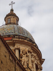 Stone atlante (telamon) sculpture with raised arms supporting the cornice beneath the tiled dome of the Church of Carmine Maggiore in Palermo, Sicily, photographed from below. © Warholderribado 