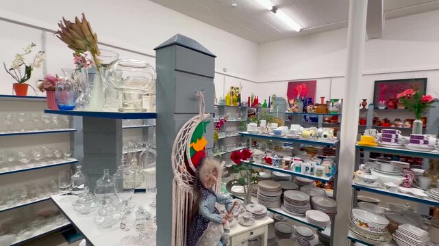 Glassware, plates, cups, and vases are available for selection in fully stocked display cases, panning shot