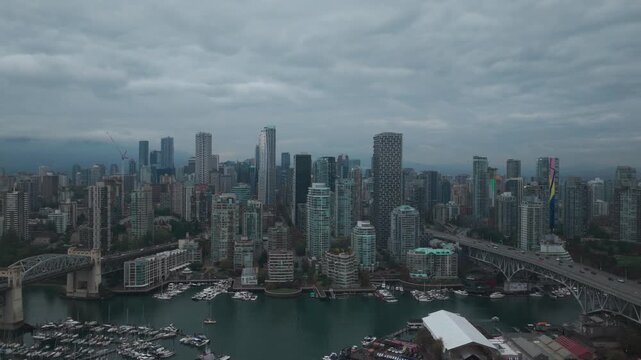 Wide dolly aerial shot of False Creek with the Burrard and Granville bridges on a rainy morning in Vancouver, British Columbia, Canada. 4K