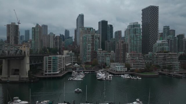 Low dolly aerial shot of a water taxi traveling through False Creek on an overcast day in Vancouver, British Columbia, Canada. 4K