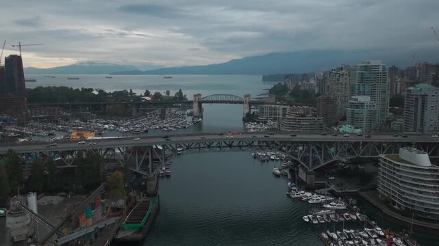 Descending close-up aerial shot of the Granville and Burrard bridges across False Creek on a rainy morning in Vancouver, British Columbia, Canada. 4K