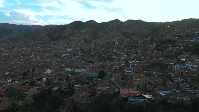 Cusco colorful buildings cityscape buildings streets mountains hillside Pucyura Peruvian Andes Peru aerial drone sunset late afternoon rainy season clouds blue sky forward upwards motion