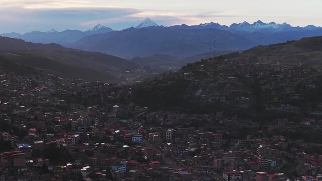 Cusco Pucyura city buildings Peruvian Andes Mountains range Peru aerial drone Mount Humantay Salkantay sunset late afternoon rainy season clouds tall colorful buildings cityscape forward pan up motion
