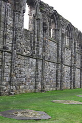 Fototapeta premium Atmospheric landscape of St Andrews Abbey in Scotland, crumbling gothic architecture surrounded by a haunting graveyard beneath overcast coastal skies.