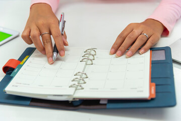 Close up view  woman sit at table hold take  notes to paper notebook working .businesswoman