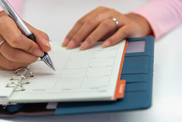 Close up view  woman sit at table hold take  notes to paper notebook working .businesswoman