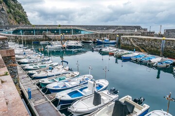 Obraz premium Small Fishing Boats and Leisure Yachts Docked in Harbor with Stone Wall Breakwater, Elantxobe, Spain