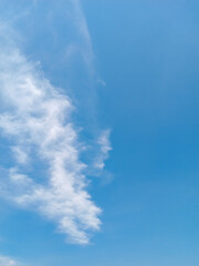 Soft white clouds stretch across a bright blue sky, creating a calm and airy atmosphere with abundant negative space ideal for text or design elements.