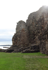 Atmospheric landscape of St Andrews Abbey in Scotland, crumbling gothic architecture surrounded by a haunting graveyard beneath overcast coastal skies.