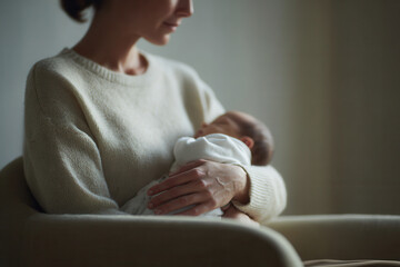 tender moment of mother gently rocking her newborn baby in cozy chair by window