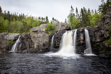 Fototapeta premium Waterfall Cascading Over Rock Formations into a Quiet Pool