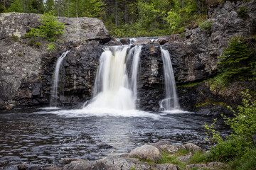 Waterfall Cascading Over Rock Formations into a Quiet Pool