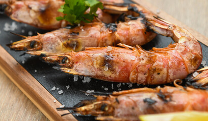 Grilled tiger prawns with lemon and parsley on wooden table