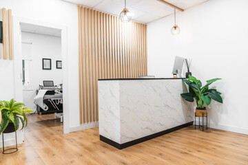 Modern physiotherapy clinic reception featuring a marble desk and wooden wall accents, offering...