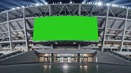 Massive greenscreen billboard on modern illuminated stadium exterior creating versatile advertising space in large outdoor arena setting