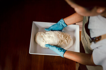 Top view of woman hand with glove preparing bread dough iin kitchen..