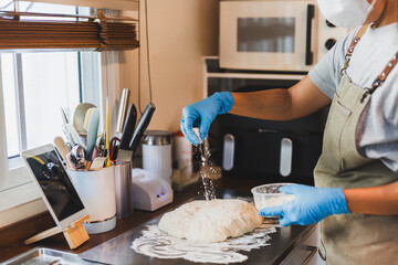 Female chef sprinkling flour on dough in home kitchen