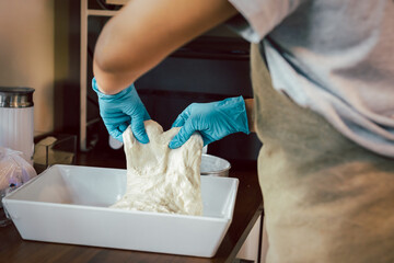 Woman hand with glove preparing bread dough on wooden table.