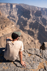 Traveler contemplating vast jebel shams canyon in oman