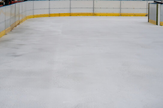 Empty ice rink with yellow boards in a winter urban setting, prepared for skating during seasonal holiday attractions - Powered by Adobe