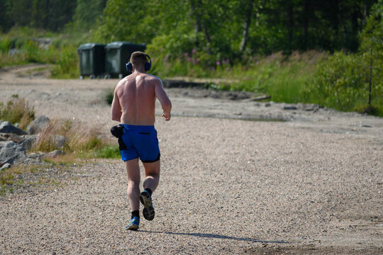 Man Runs by Lake with Headphones in Summer Nature