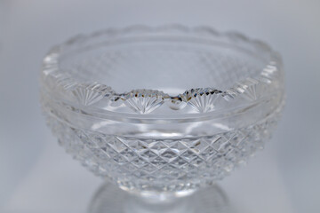 Macro defocused texture view of an antique hand-cut footed lead crystal glass bowl, with scalloped edge