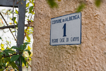 A ceramic plaque on the wall of a building in Italy, in the commune of Albenga, with the number 1