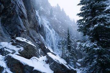 Frozen waterfall cascading down rocky cliffs in winter landscape