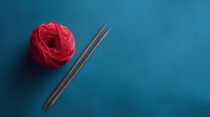 Red Yarn Ball and Knitting Needles on Blue Background