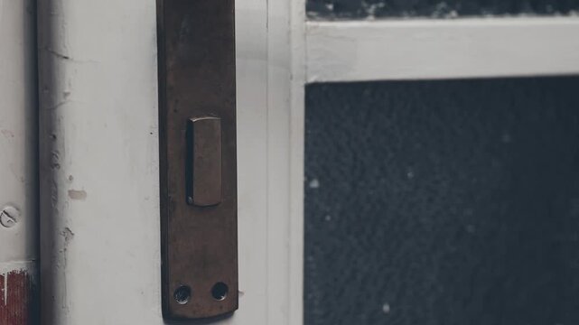 Detail of searching for fingerprints on crime scene by criminologist around door handle
