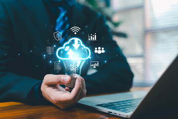Business professional holding glowing light bulb with cloud computing icons, symbolizing innovation, data storage, cybersecurity, analytics, and modern digital transformation solutions in technology.