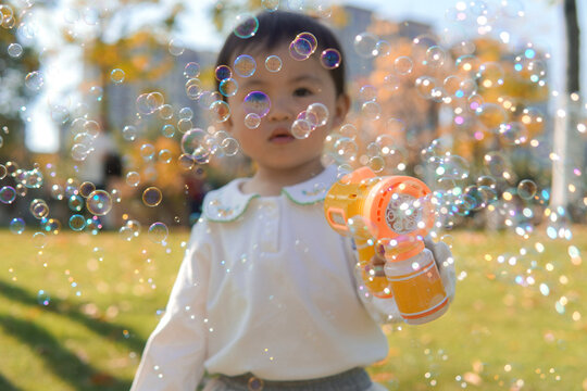 A child plays with a bubble blower, creating bubbles in an autumn park. - Powered by Adobe