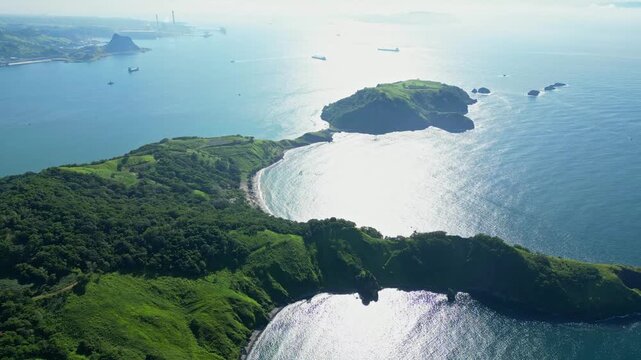 Slow‑rise aerial of Five Finger Cove in Mariveles, Bataan, lifting above rugged green cliffs and turquoise waters to reveal the sweeping coastline and serene ocean horizon.