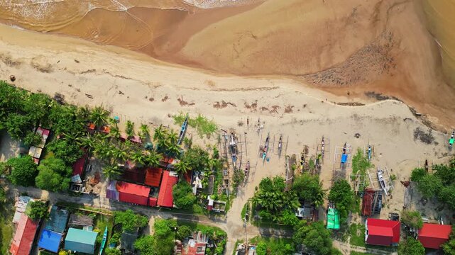 Rising top‑view aerial showing sandy shoreline of Quinawan Beach with waves rolling onto the coast, gradually revealing the coastline town framed by lush hills in Mariveles, Bataan.