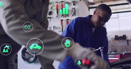 Leaning mechanic in blue coveralls using hand tool at open engine bay, with floating green icons
