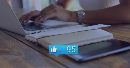 Typing female hands in ribbed top on wooden cafe table with laptop notebook tablet alert bubble