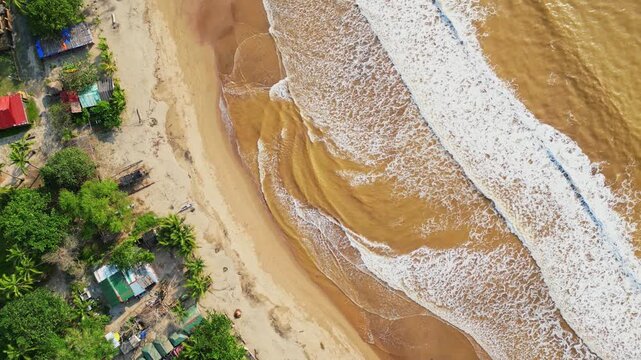 Top‑view rotating aerial highlighting waves rolling onto the sandy shoreline, capturing the dynamic coastal scenery and tranquil atmosphere of Quinawan Beach in Mariveles, Bataan, Philippines.
