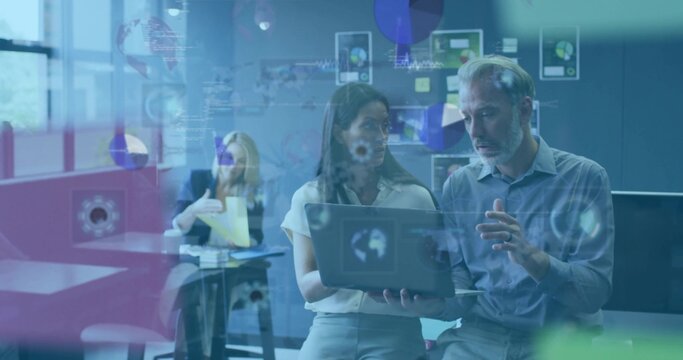 Collaborating two colleagues in business attire viewing laptop in office with glass showing data