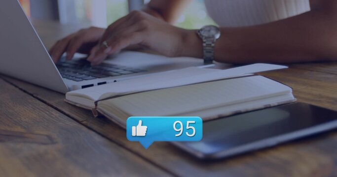 Typing female hands in ribbed top on wooden cafe table with laptop notebook tablet alert bubble