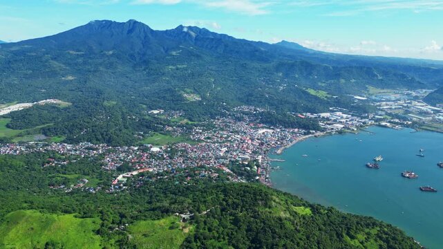 Aerial of Mariveles town in Bataan, showcasing the coastal settlement and harbor with Karagatan View Point rising in the background against lush green hills and mountains.